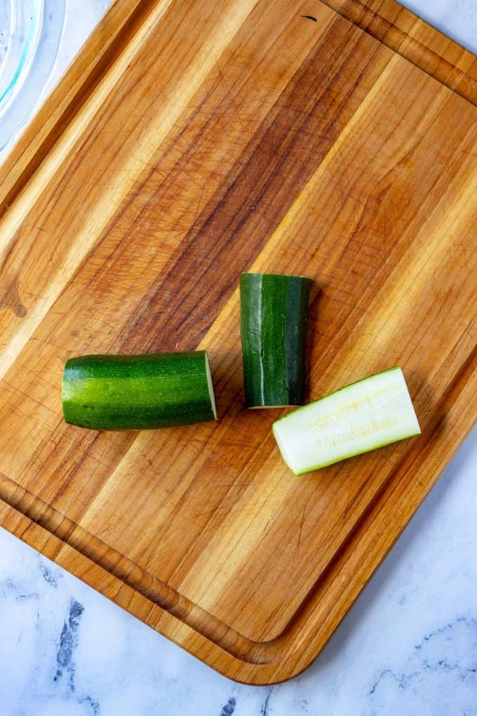 Overhead photo of a cutting board with a zucchini being sliced into fries.