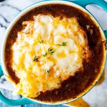 Close up square photo of keto french onion soup in a blue crock.