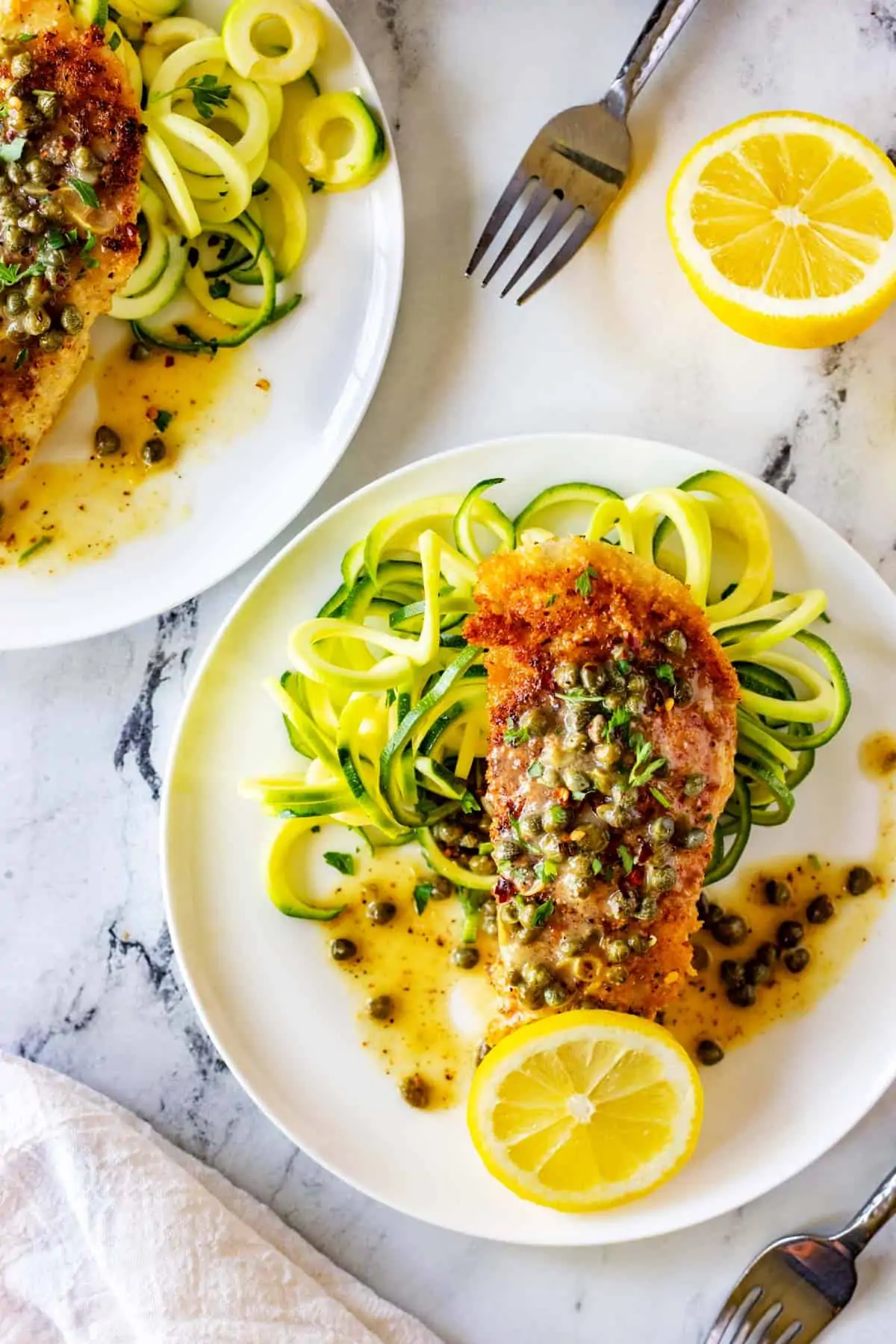 Overhead photo of Keto Chicken Piccata on a bed of zucchini noodles garnished with lemon and parsley.