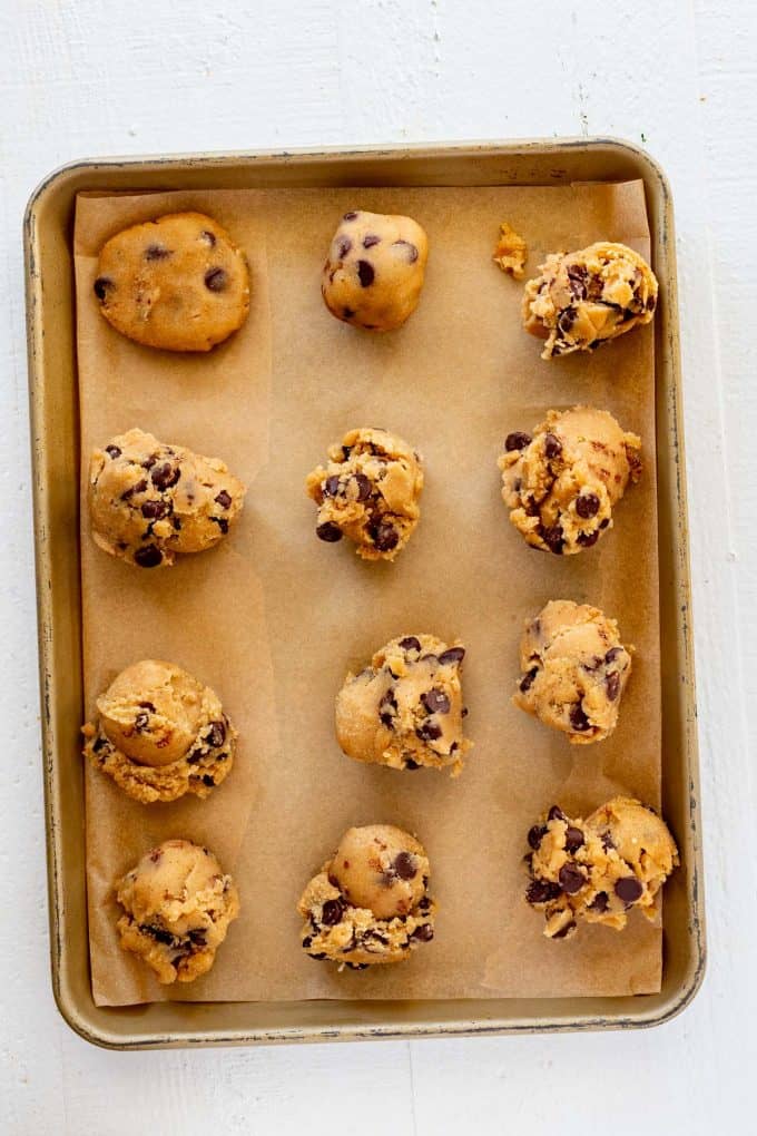 Keto chocolate chip cookies that have been dropped on a parchment lined baking sheet.