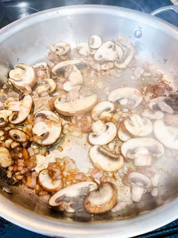 Photo of mushrooms being cooked in a large skillet.