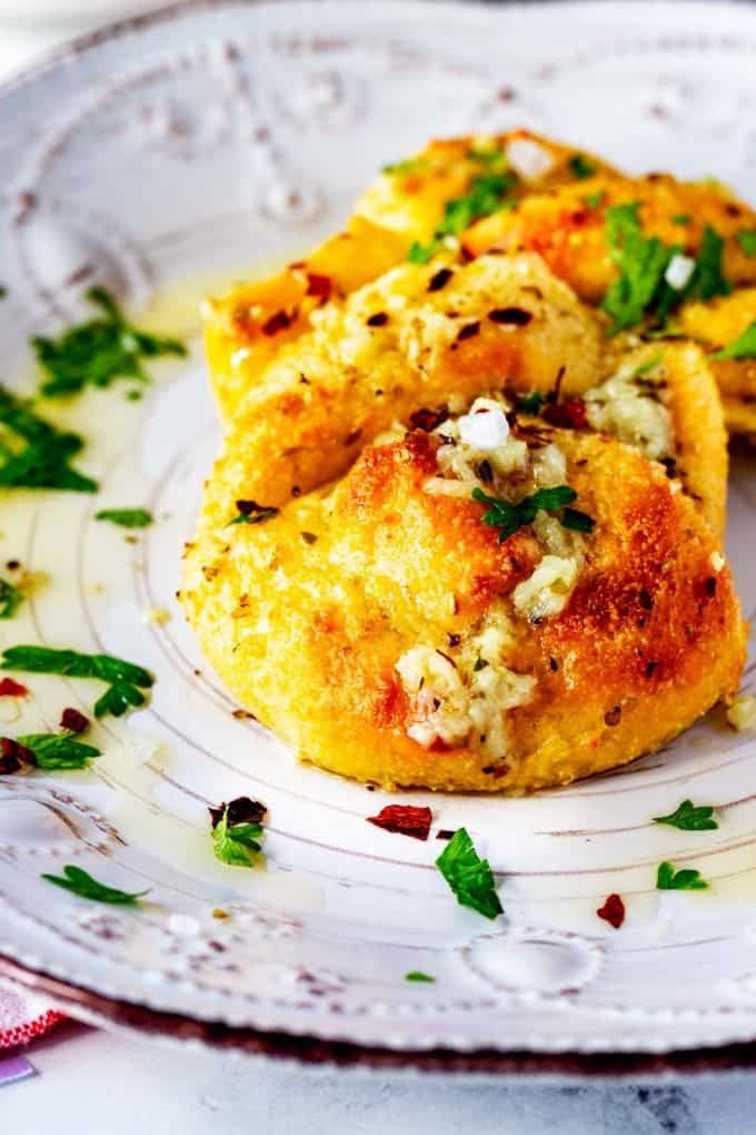 Close up photo of keto garlic knots on a white plate garnished with parsley.