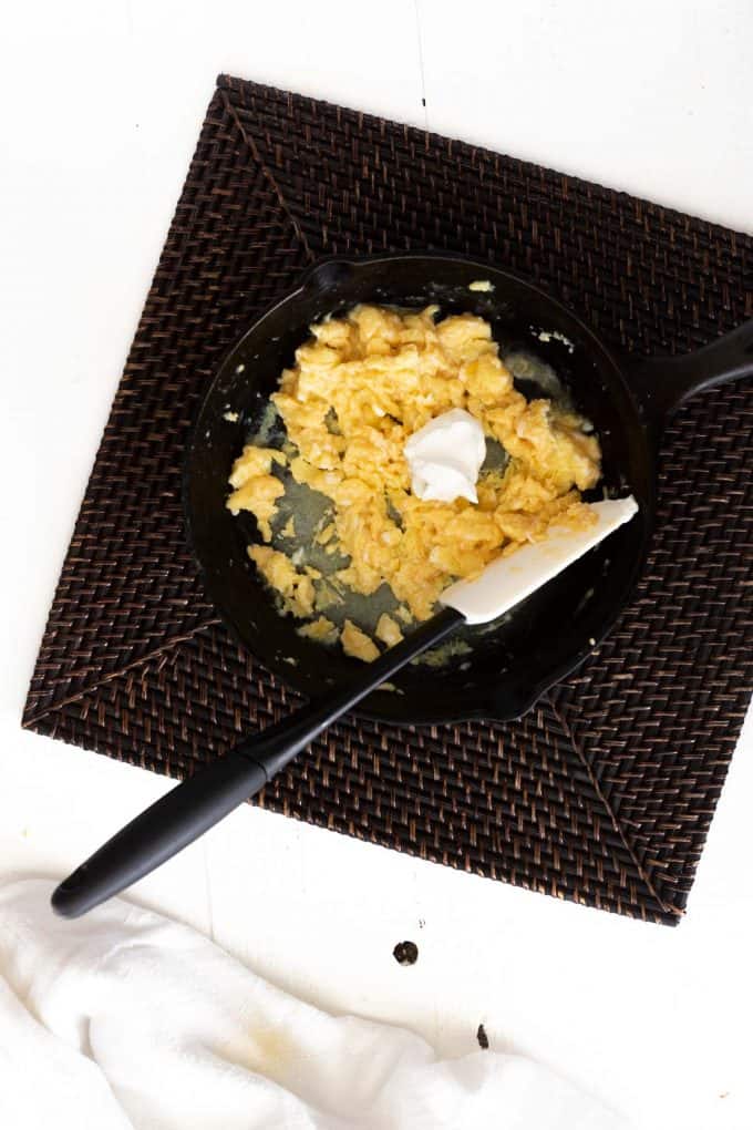 Photo of eggs being scrambled in a cast iron skillet.