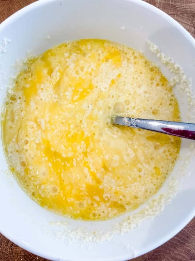 Photo of eggs and parmesan being whisked together.