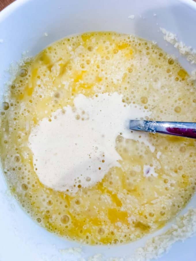 Photo of warm cream being added to an egg and parmesan mixture.