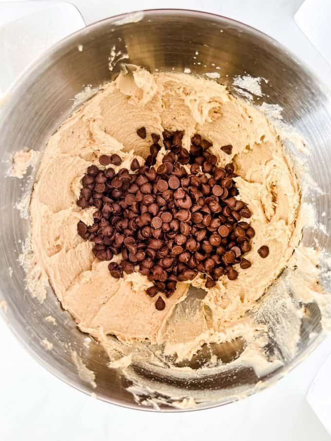 Photo of chocolate chips being added to cookie dough.