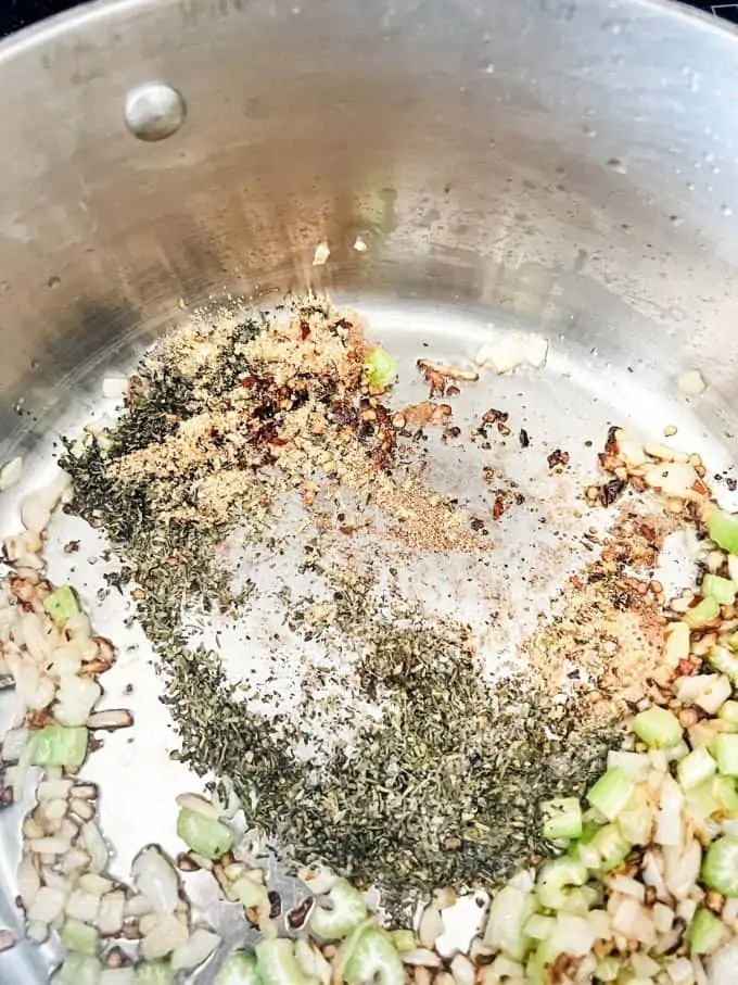 Seasonings added to onion and celery in a stockpot.