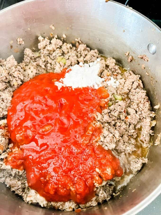 Finely chopped tomatoes and Swerve that has just been added to browned ground beef, seasonings, celery, and onions.
