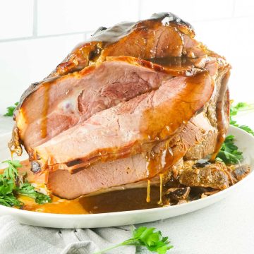 Square side photo of keto ham on a serving platter with a brown sugar glaze poured over it.