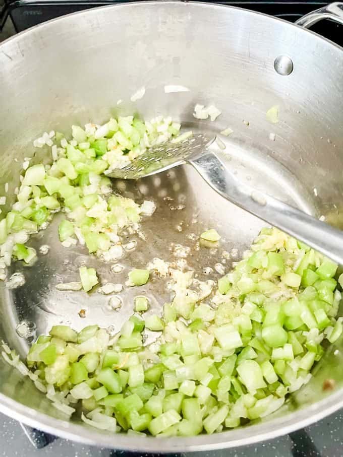 Photo of onions and celery that have been cooked in oil that are starting to soften.
