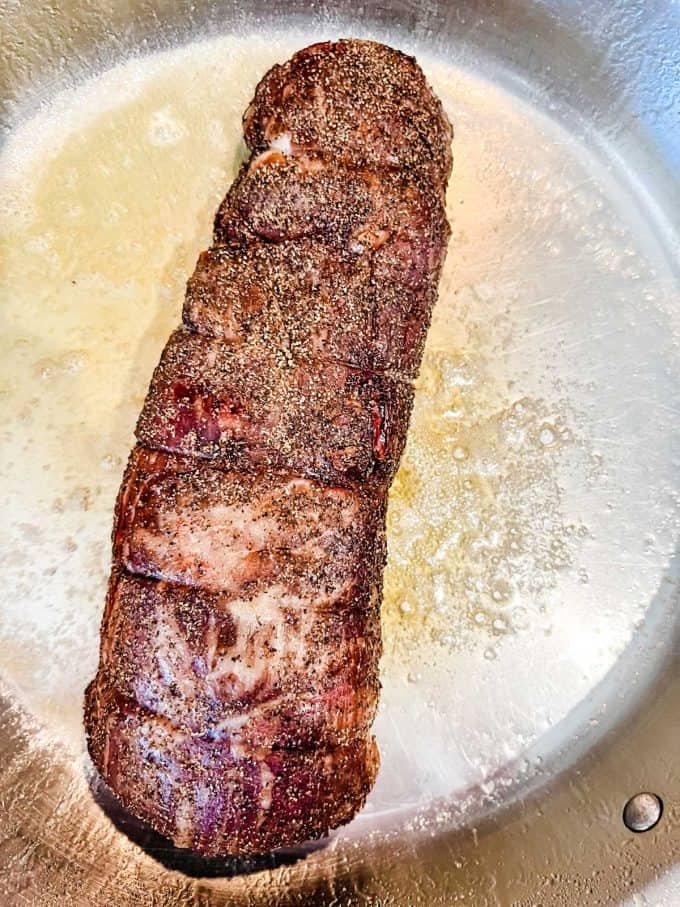 Photo of beef tenderloin cooking in butter and oil.