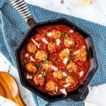 Square photo of keto meatballs in marinara garnished with parsley and parmesan.