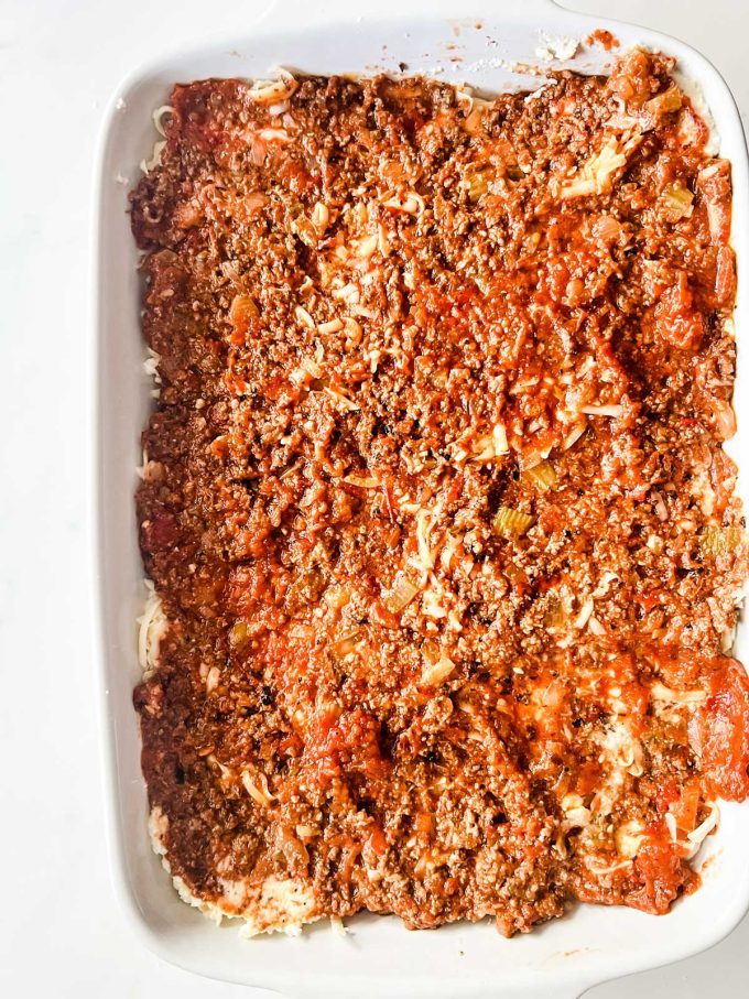 A meat sauce on top of a casserole dish of lasagna.