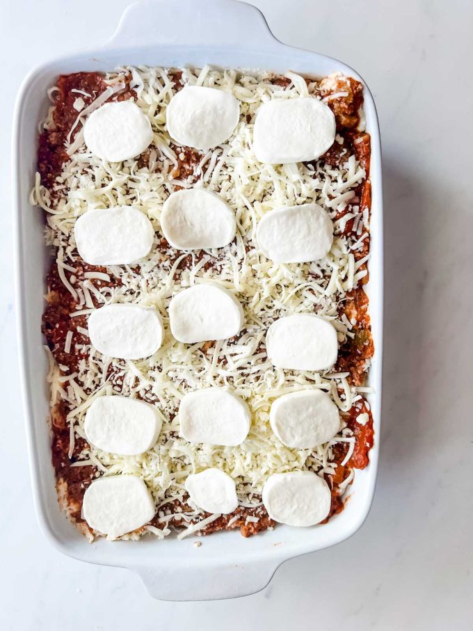 Shredded and fresh mozzarella added to the top of a lasagna.