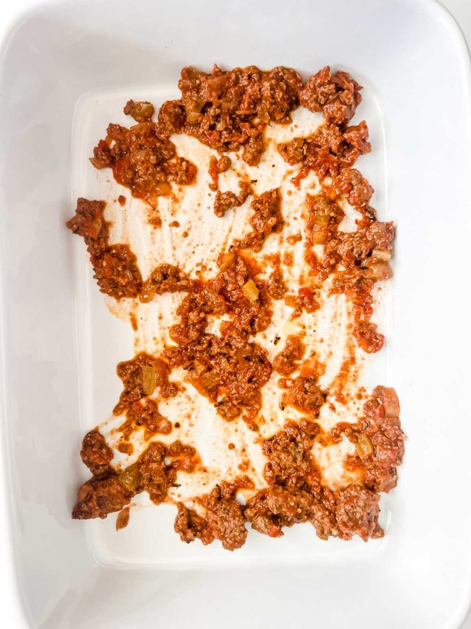 Photo of meat sauce on the bottom of a casserole dish.