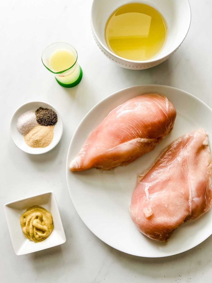 Overhead photo of chicken breast, oil, lemon juice, seasonings, and mustard in prep containers.