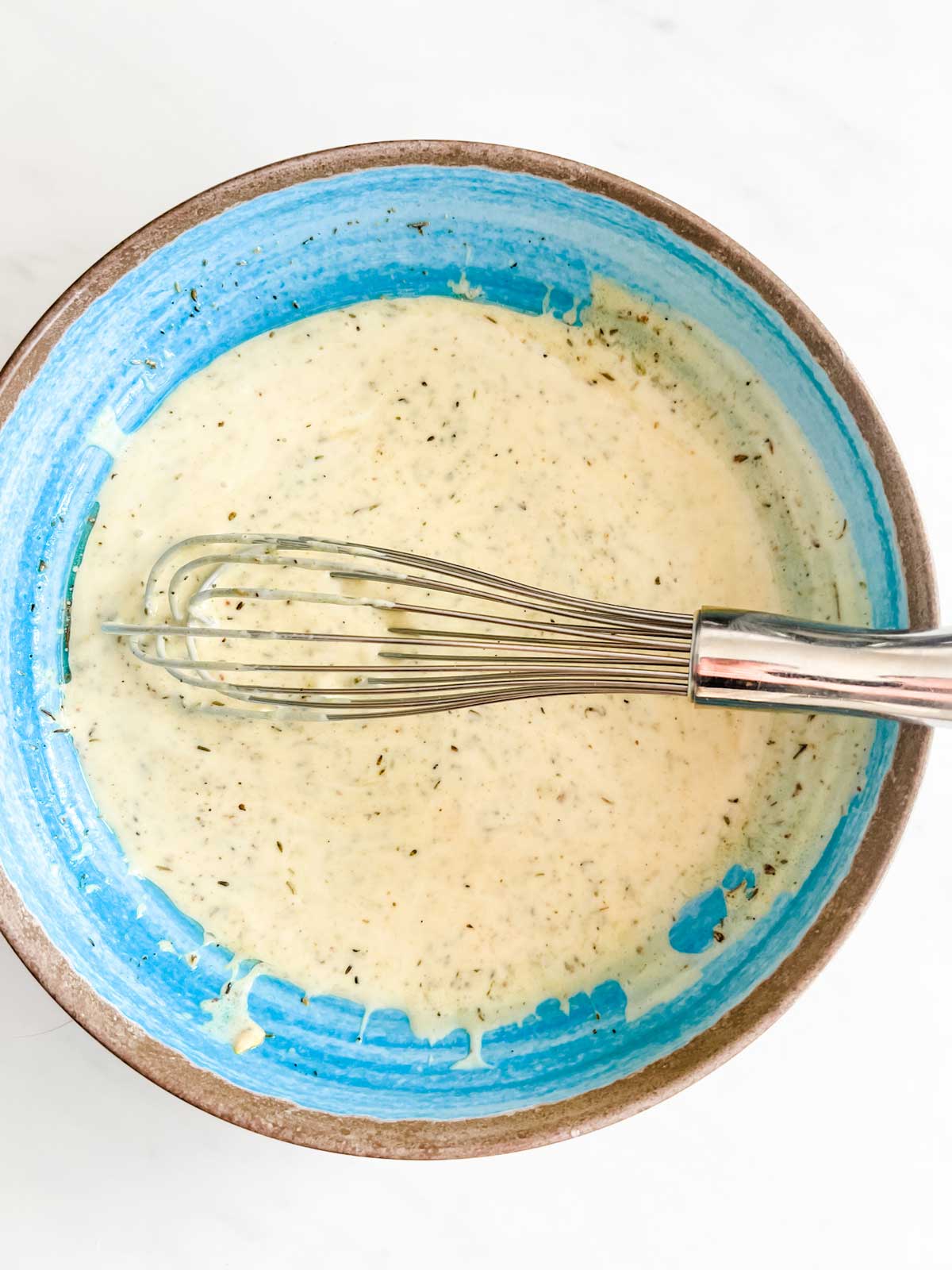 Chicken marinade being whisked together in a blue bowl.