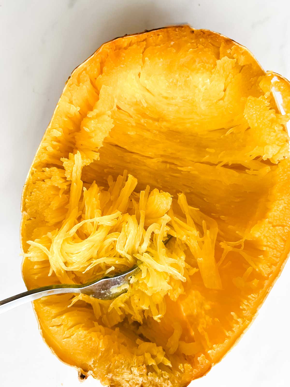 Photo of a fork in a spaghetti squash turning the flesh into "noodles".