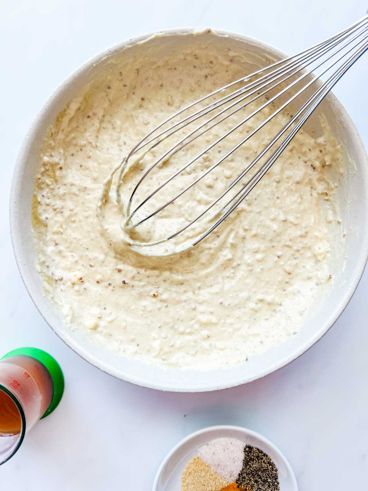 Overhead photo of a bowl with two kinds of mustard and mayo that have been whisked together.
