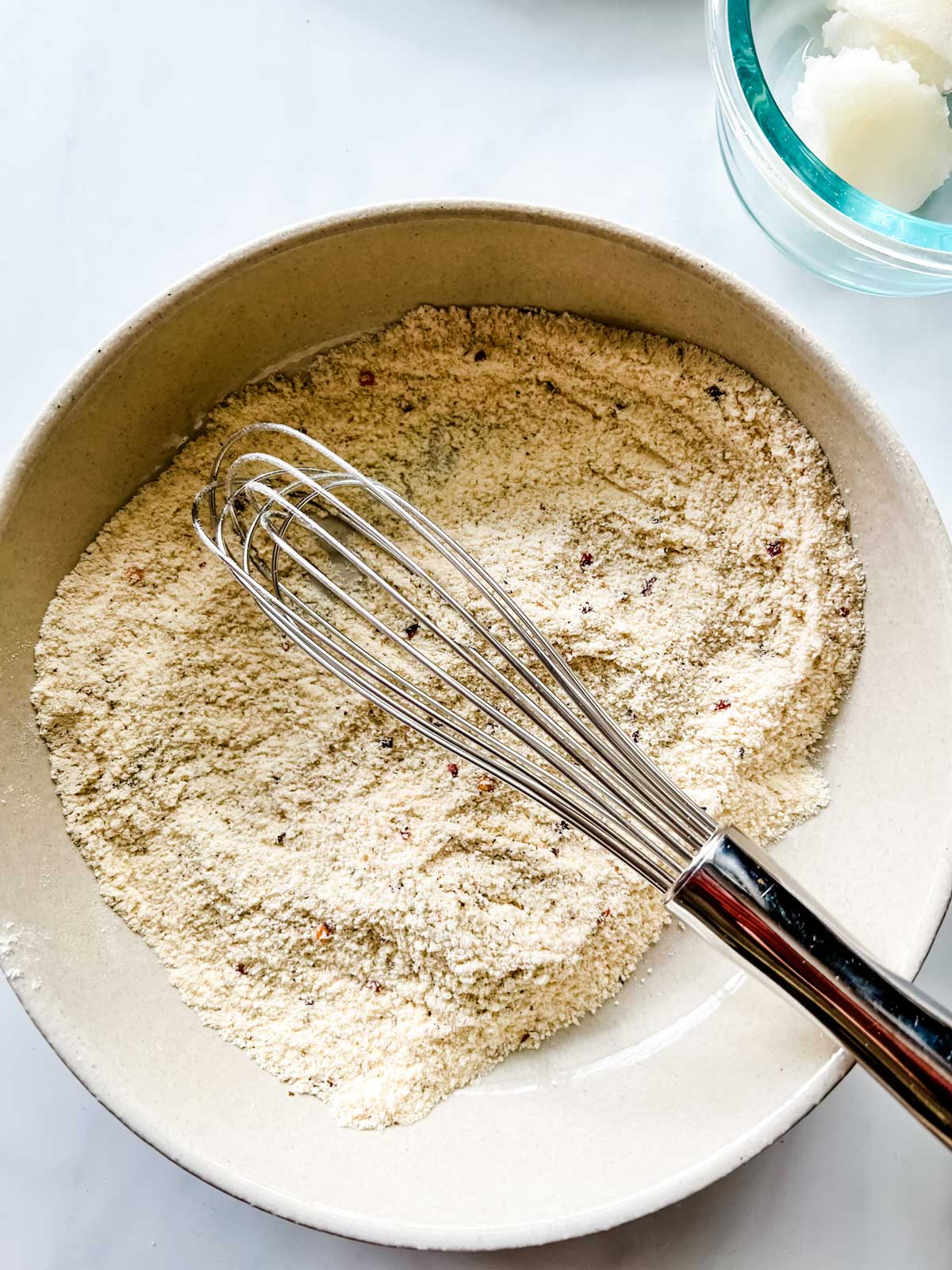Coconut flour and seasonings being whisked together in a bowl.