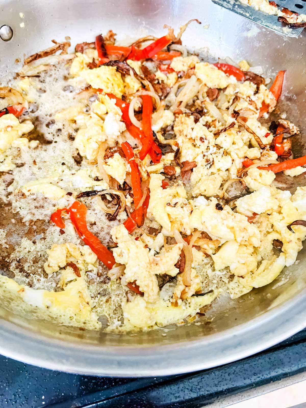 Onion, pepper, and eggs in a skillet.
