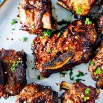 Close up square photo of air fryer short ribs on a platter garnished with parsley.