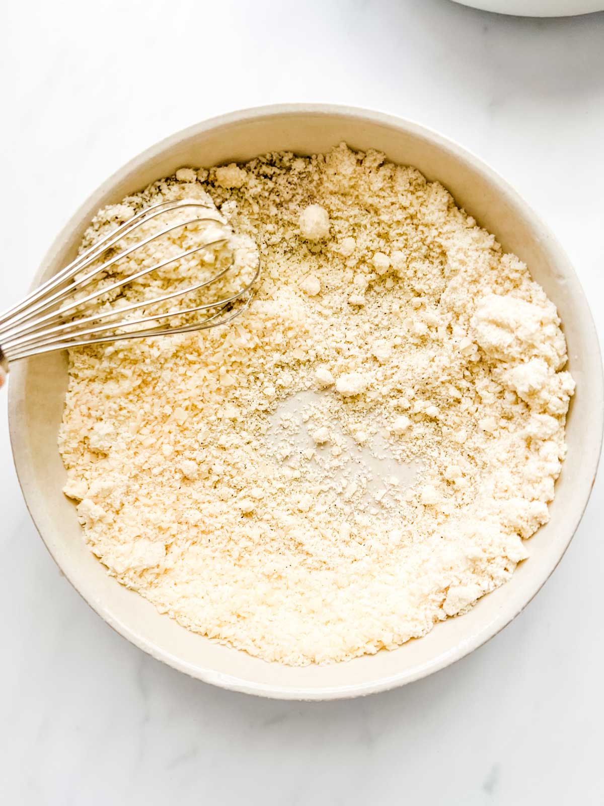 Photo of a seasoned almond flour parmesan mixture that has been whisked together in a shallow bowl.