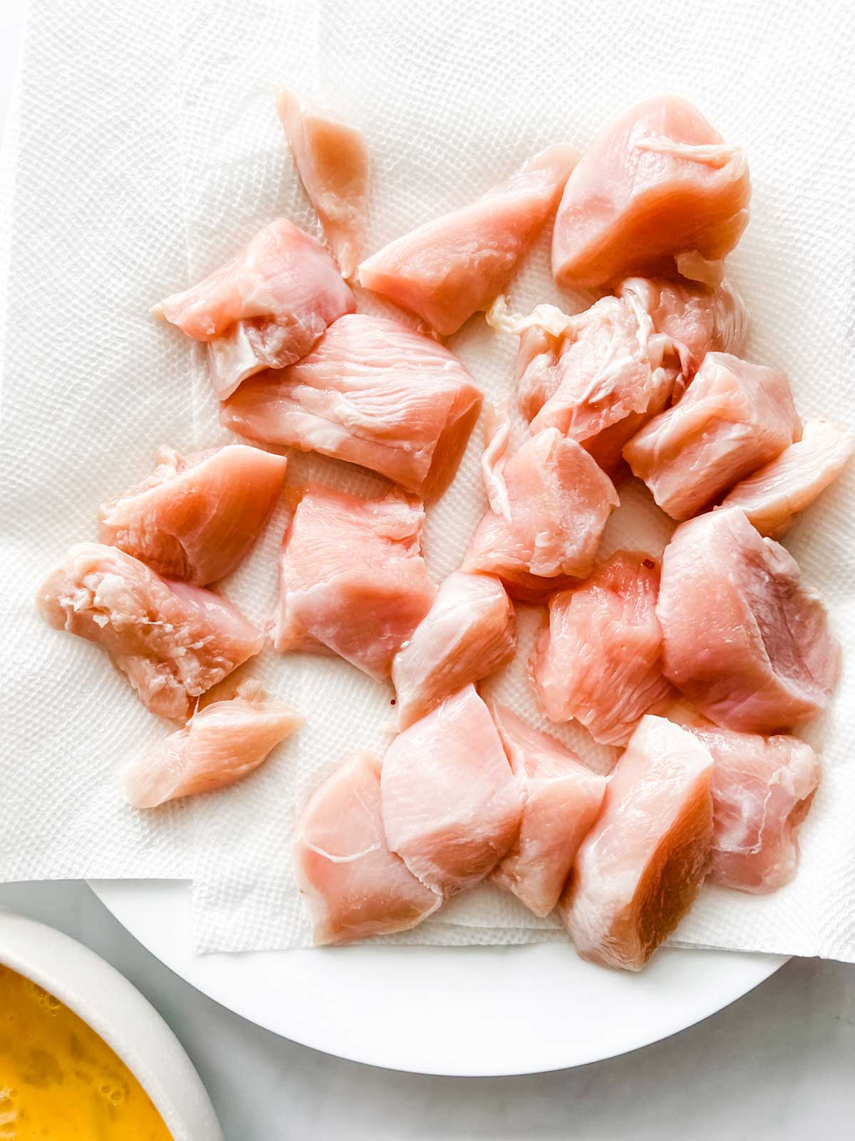 Photo of cubed chicken that is been brined sitting on a paper towel lined plate.