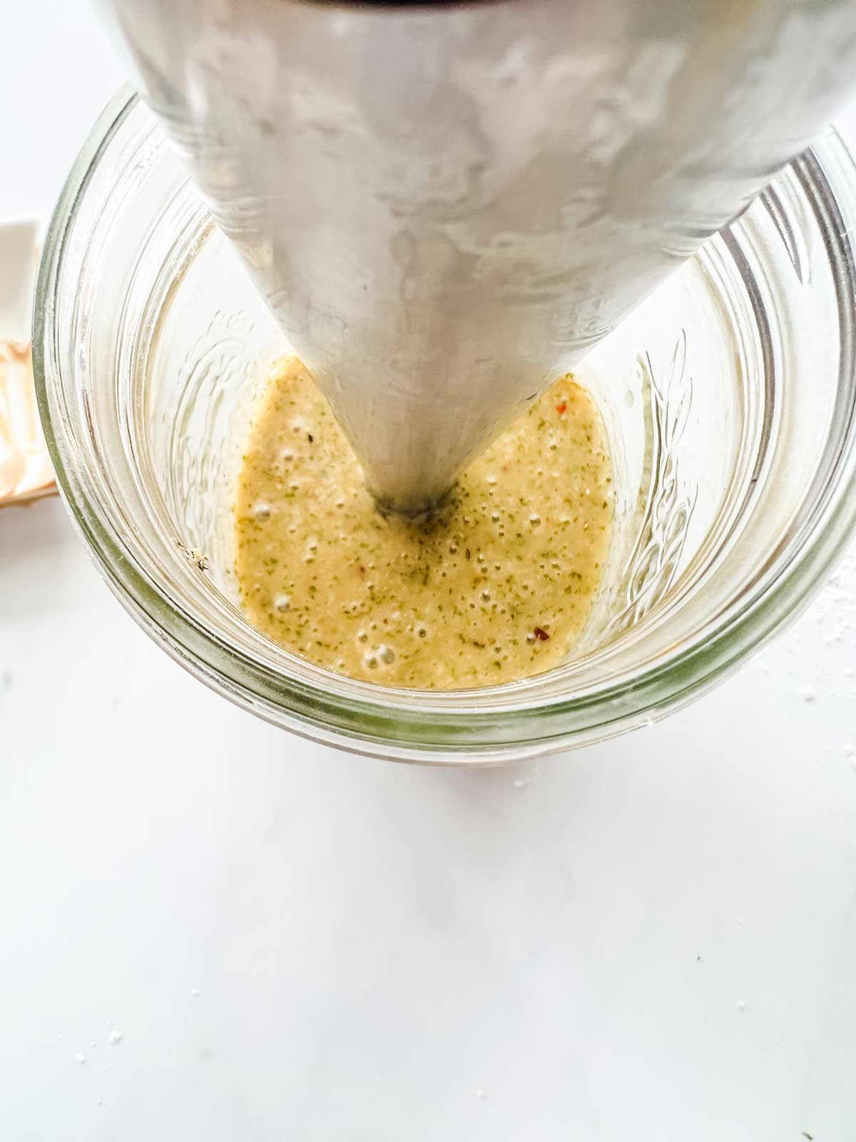 Photo of keto Italian dressing being mixed in a mason jar with an immersion blender.