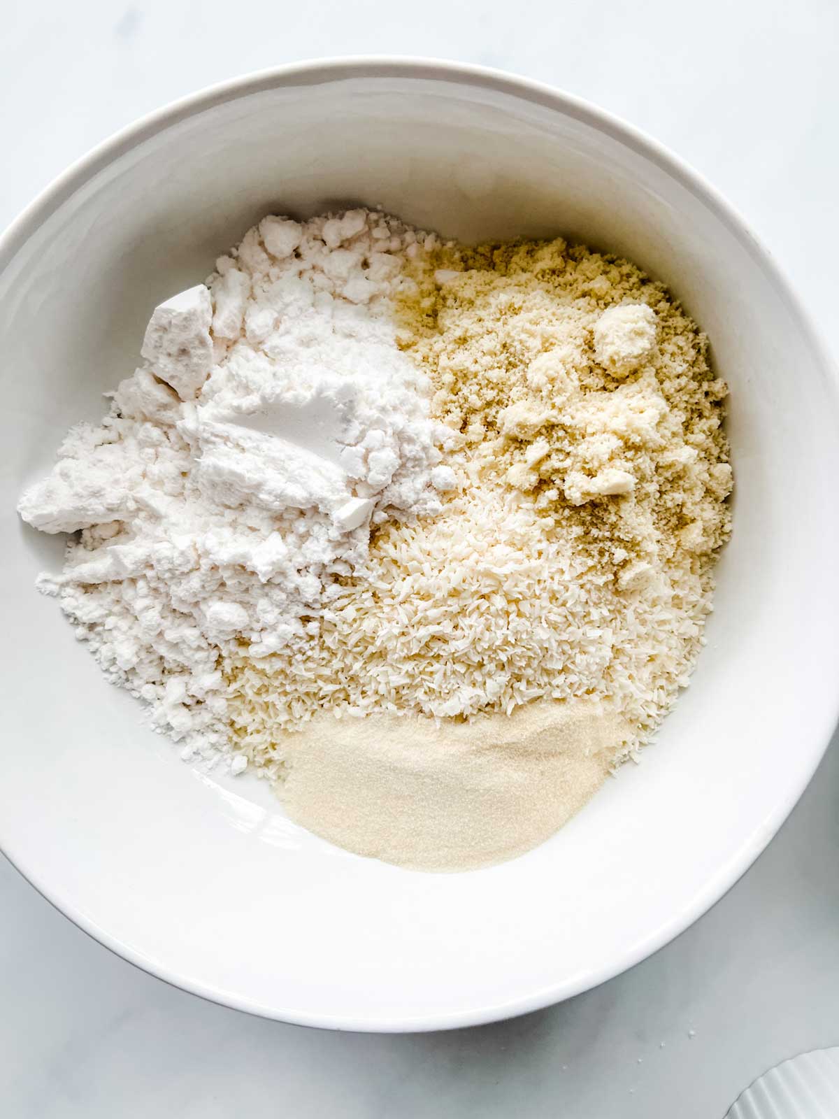 Photo of coconut, sweetener, almond flour, gelatin and salt in a bowl.