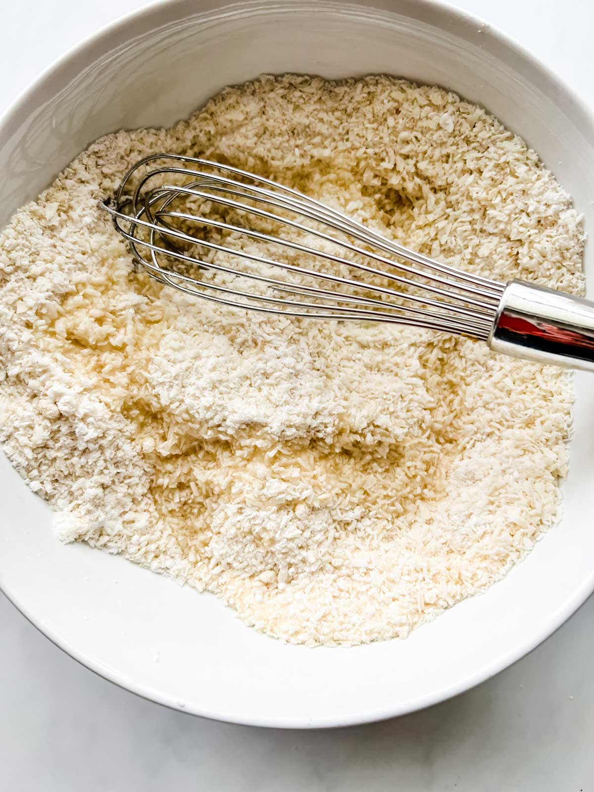 Photo of the dry ingredients for keto macaroons that have been drizzled with melted coconut oil.