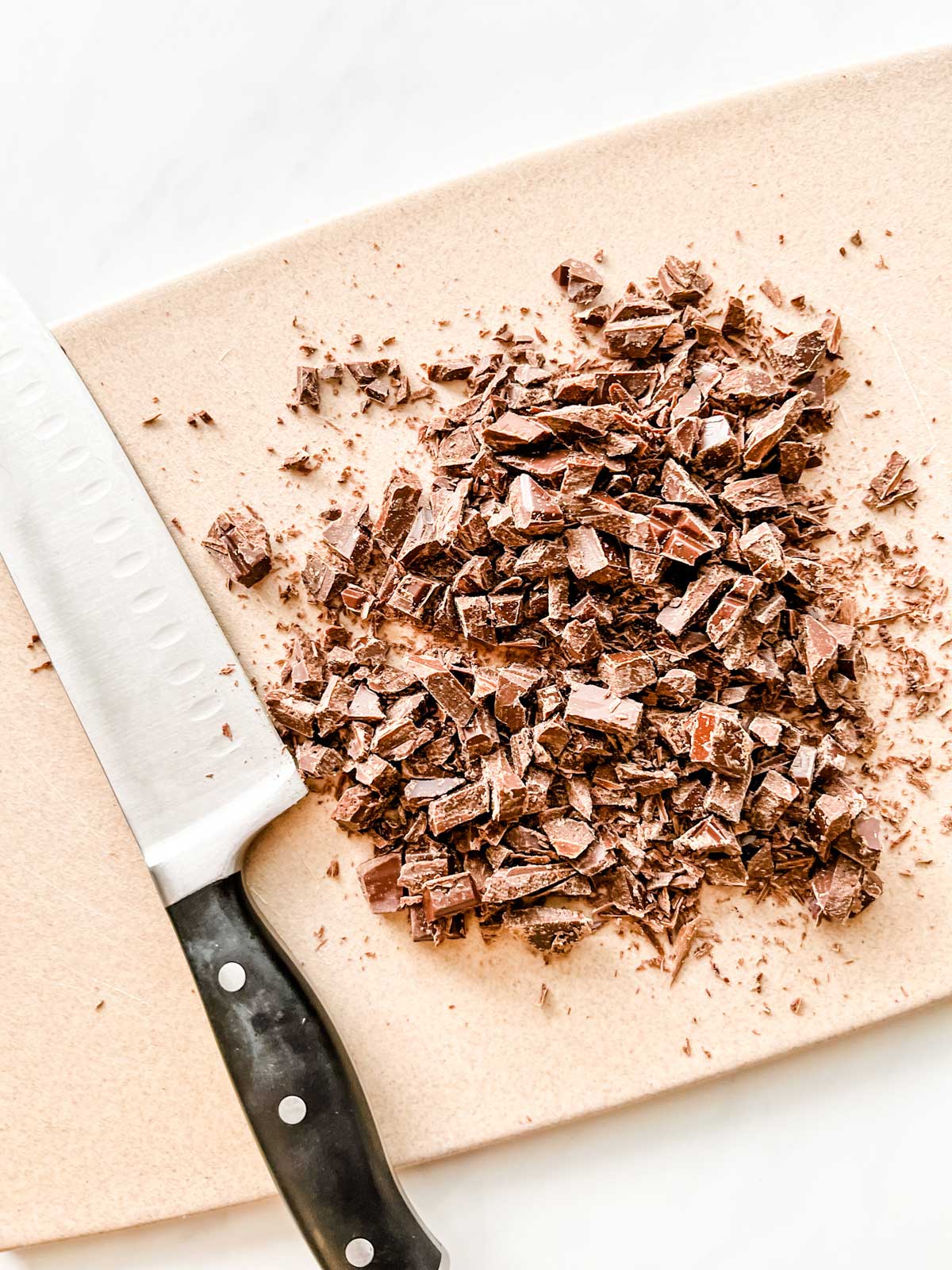 Chocolate being cut up on a cutting board.
