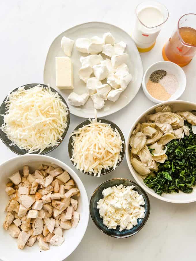 Photo of prep containers of broth, heavy cream, cream cheese, butter, seasonings, spinach, artichokes, shredded mozzarella, parmesan, crumbled feta and chopped chicken.