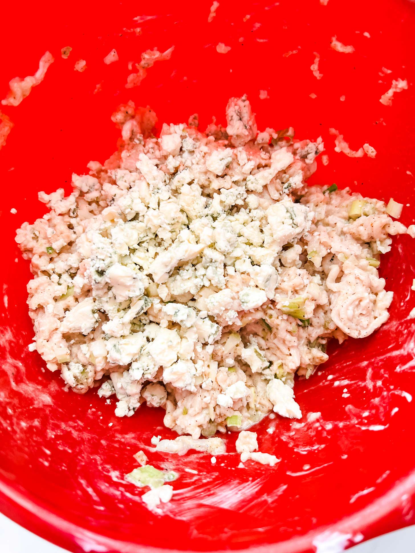 Blue cheese that has been just added to a ground chicken meatball mixture.
