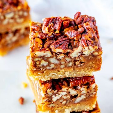 Square photo of keto pecan pie bars stacked on top of each other.