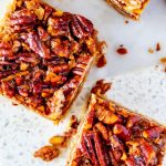 Overhead photo of keto pecan pie bars on a white marble board.