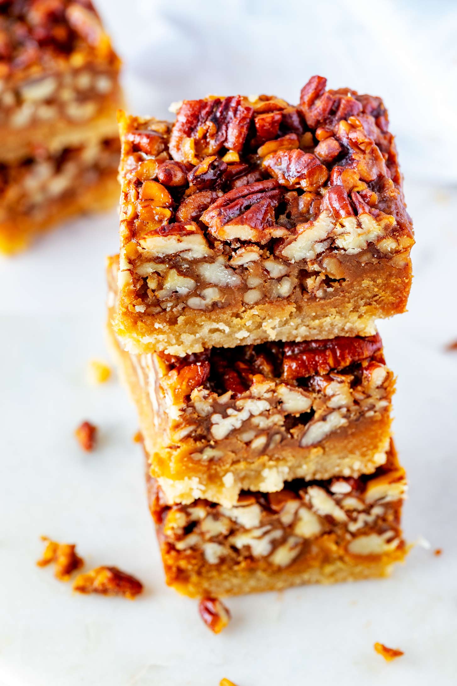 Side Photo of three stacked keto pecan pie bars with another stack of pecan bars behind it.
