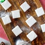 Overhead square photo of low carb keto marshmallows on a wooden cutting board siting on a red and white checked napkin.