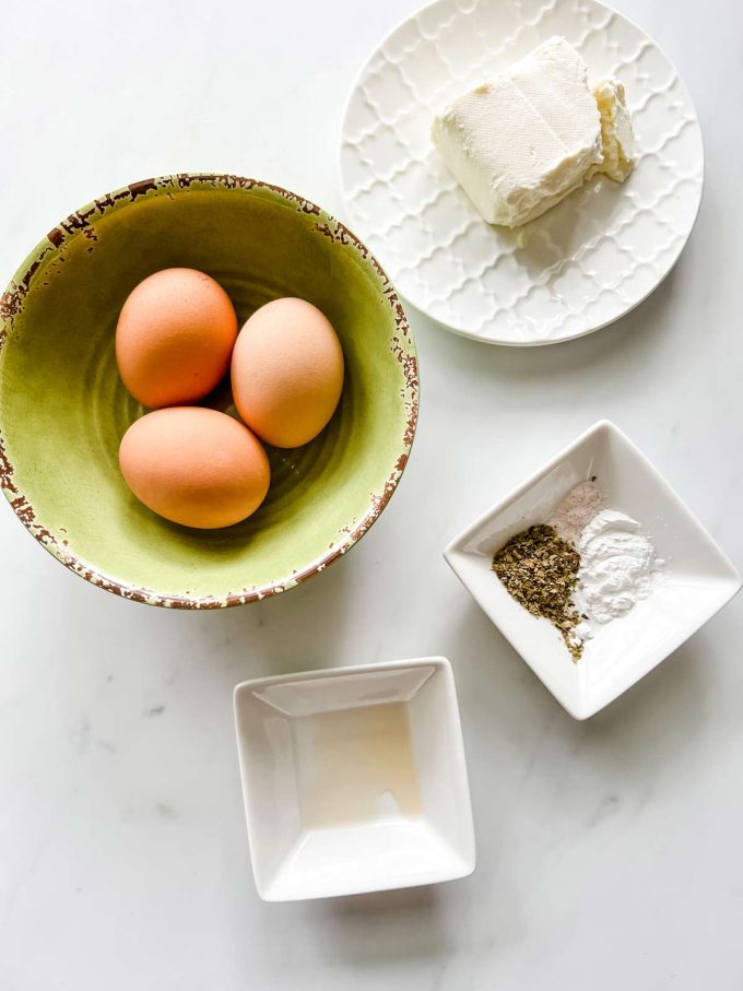 Overhead photo of eggs, cream cheese, vinegar, baking powder, and seasonings.
