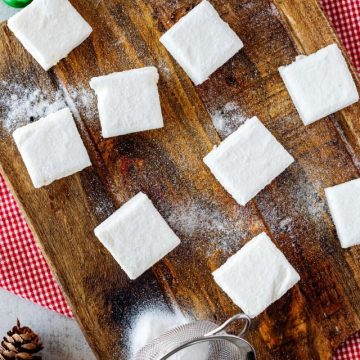 Overhead photo of a wooden cutting board with keto marshmallows surrounded by holiday decor.