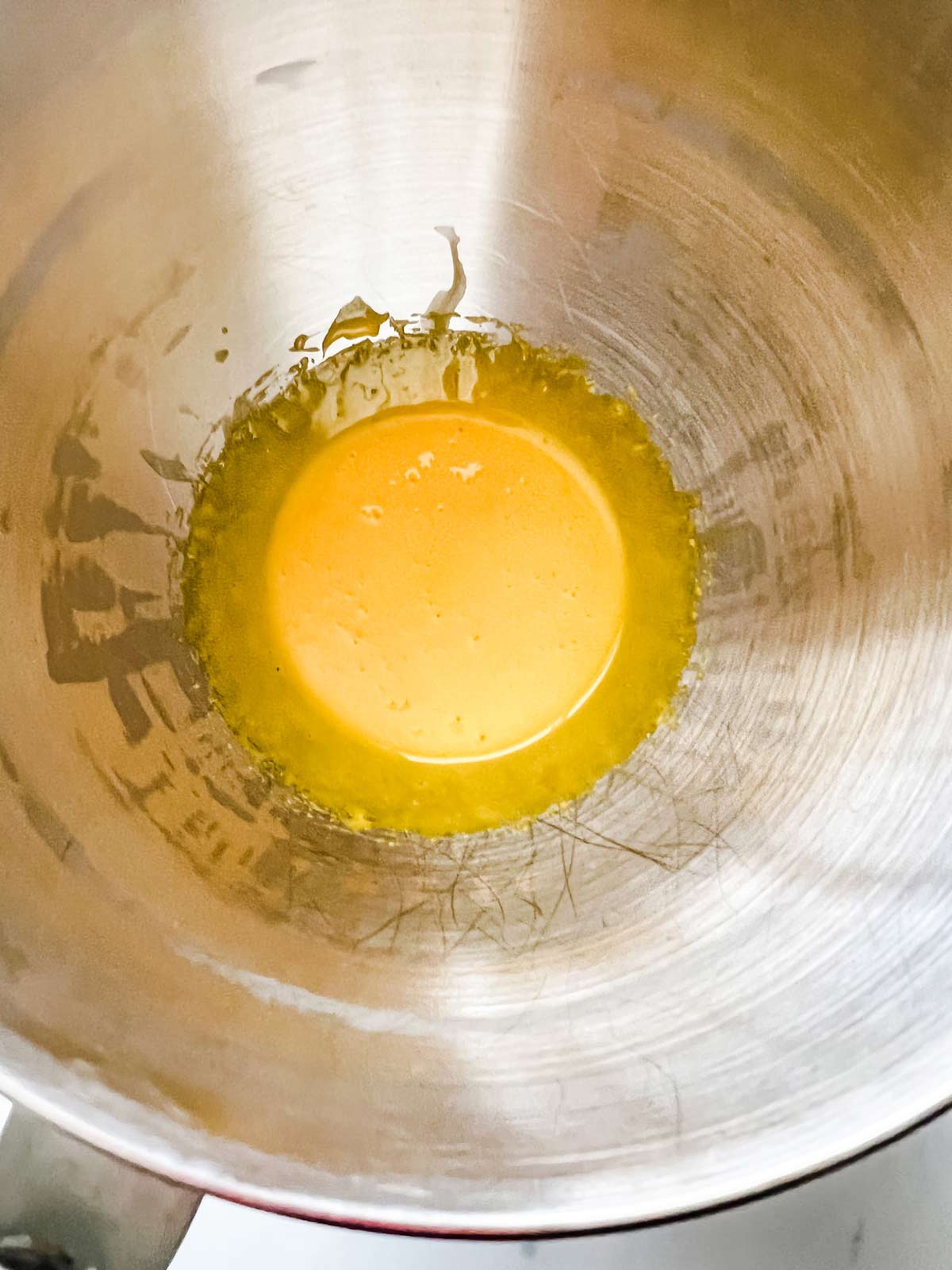 Beaten egg yolks in a metal bowl of a stand mixer.