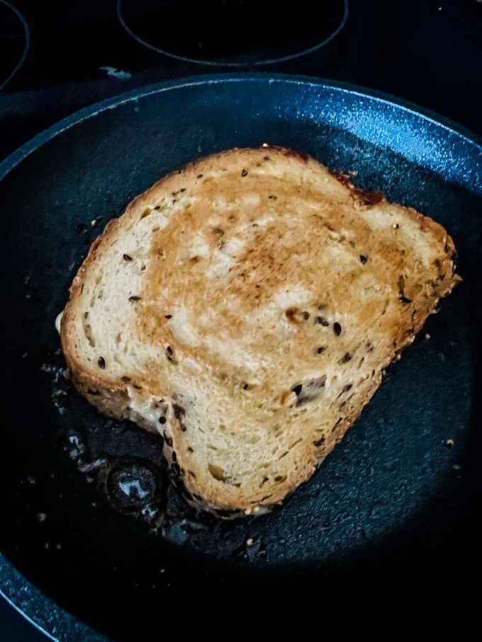 Photo of a keto grilled cheese that has been cooked on one side in a skillet.