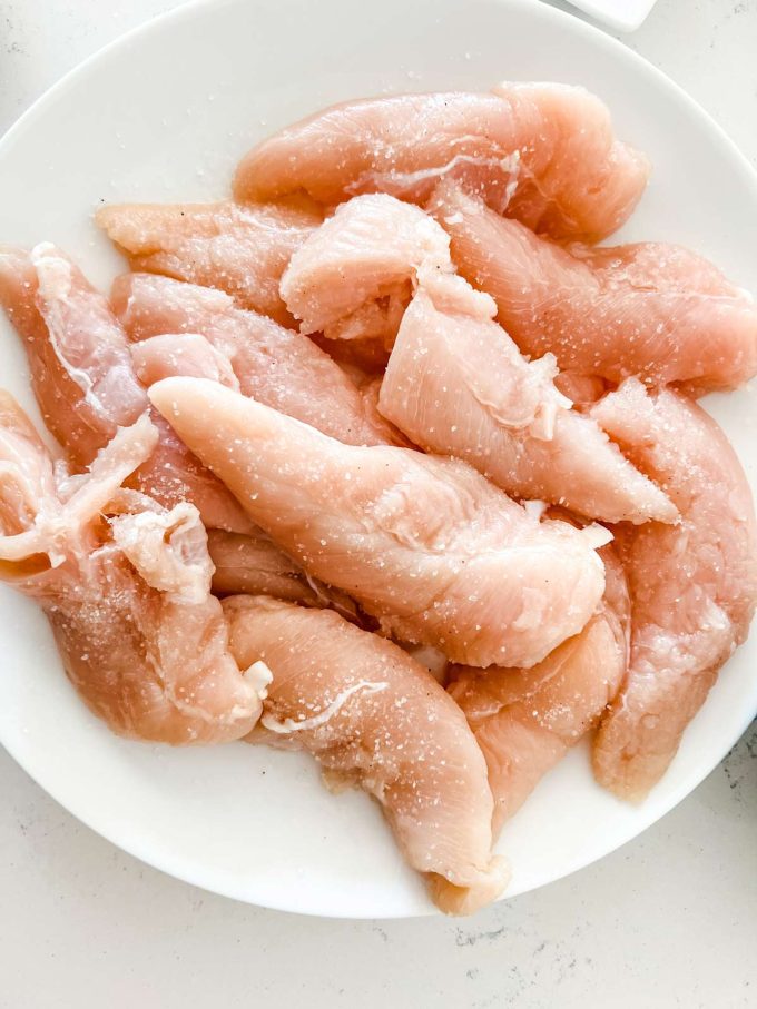 Prepped chicken tenders on a white plate.