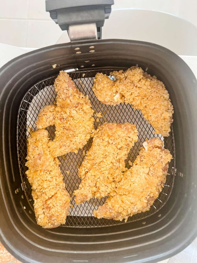 Keto chicken tenders cooking in an air fryer.