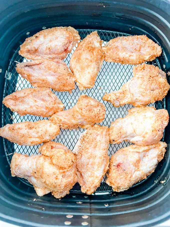 Chicken wings in an air fryer basket ready to cook.