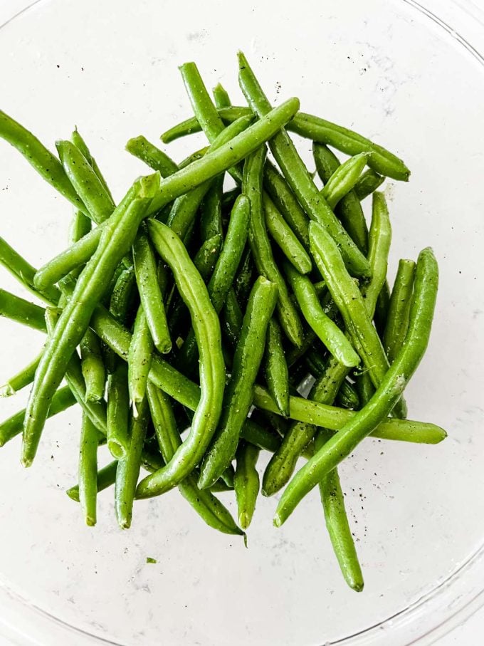 Photo of seasoned green beans in a glass bowl.