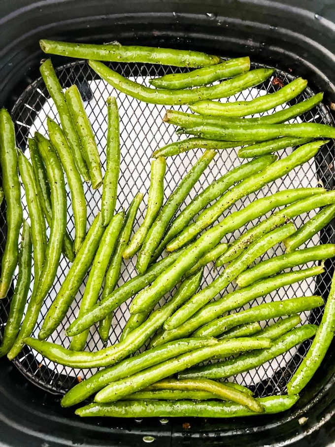 Photo of green beans in a single layer in an air fryer basket.