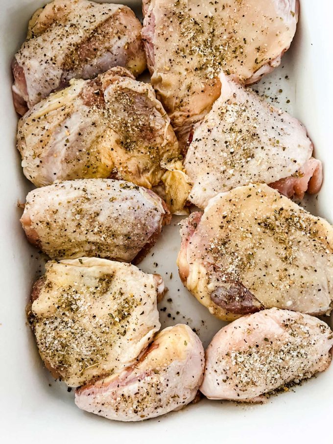 Seasoned chicken thighs in a casserole dish.