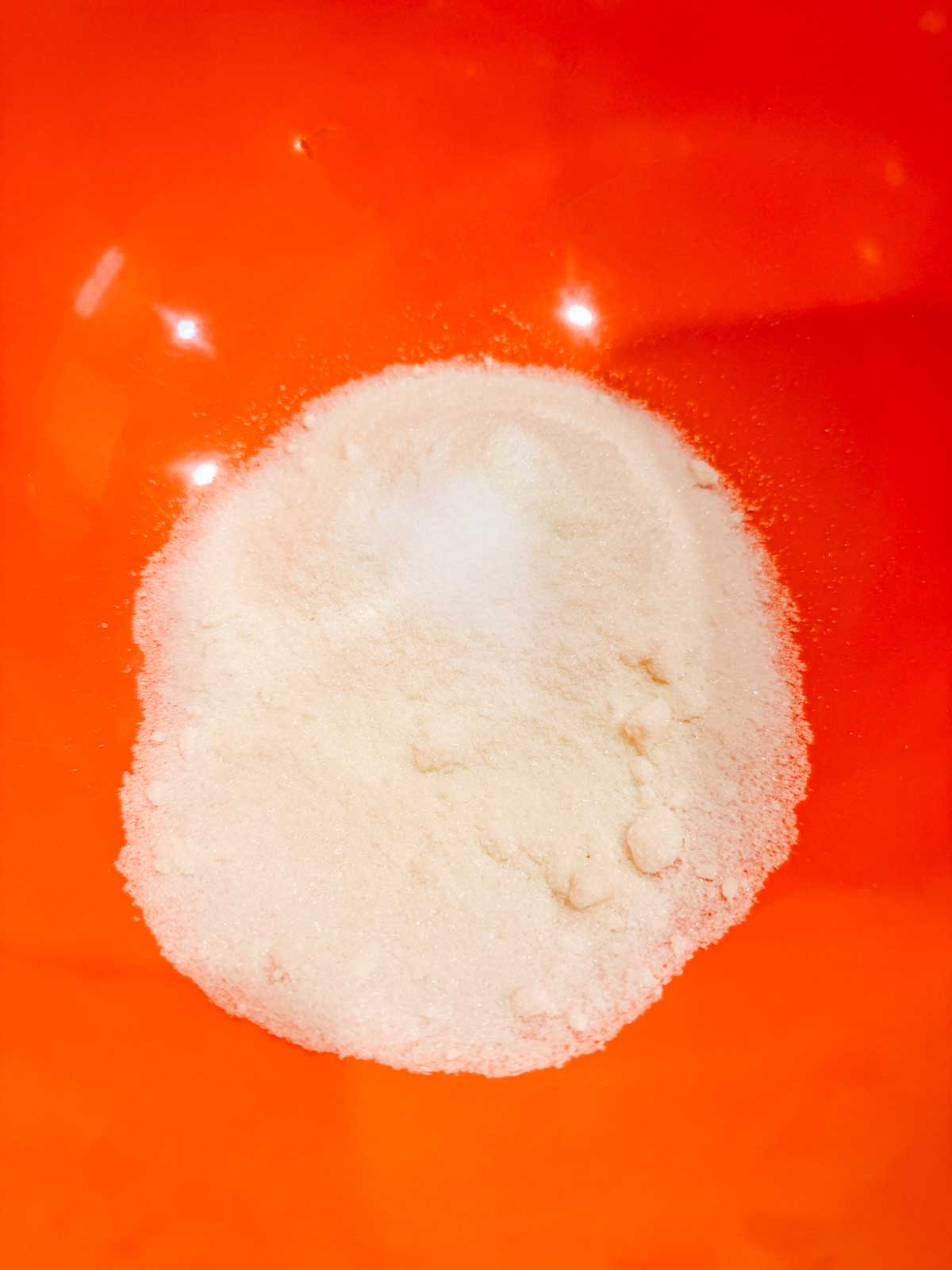 A pile of sugar substitute sits in the center of an orange mixing bowl.