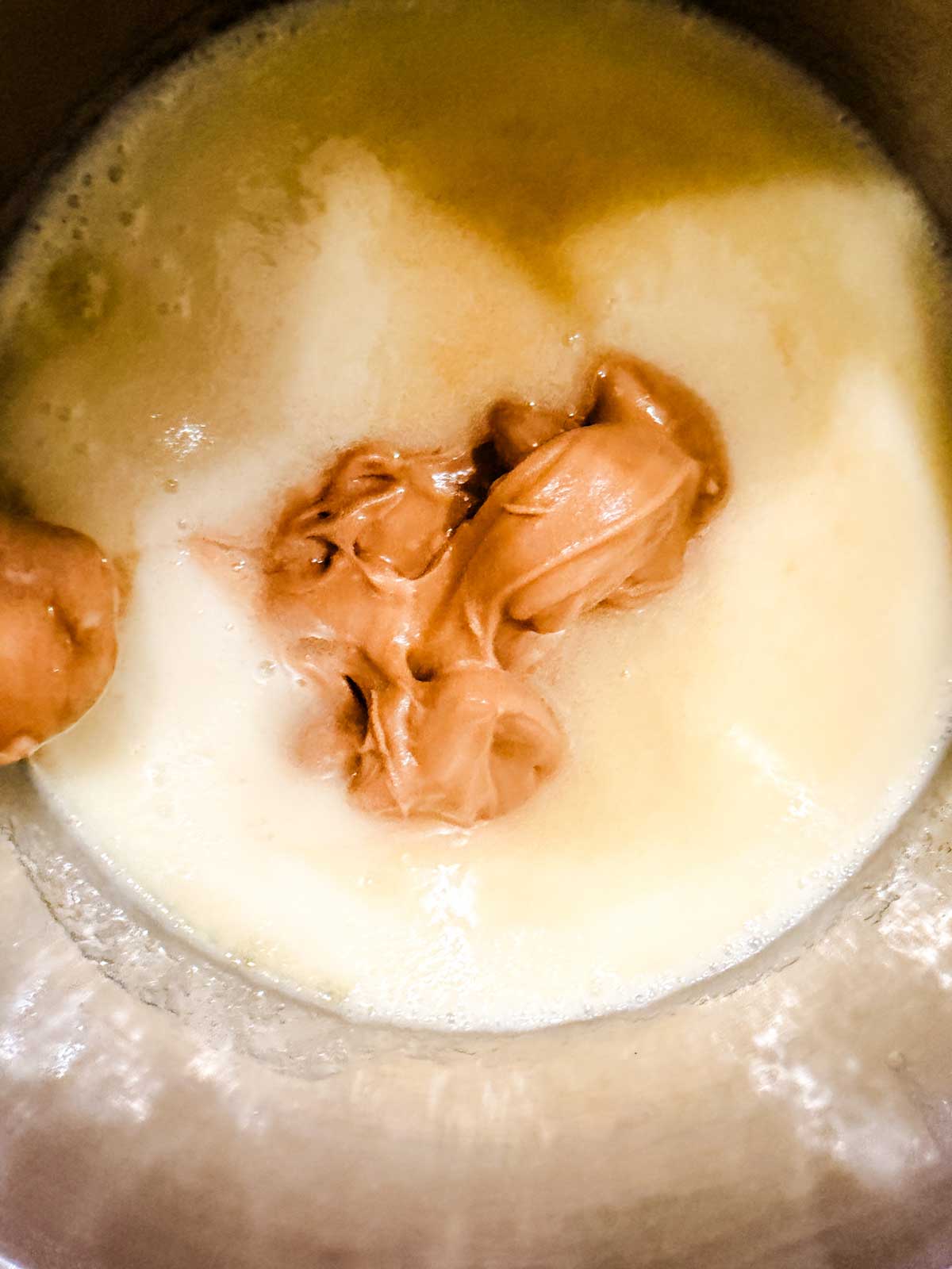 Creamy almond butter sits atop melted butter and sweetener in a saucepan.